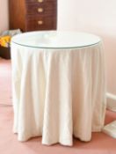A GLASS TOP CIRCULAR TABLE with fabric cover, 2ft 4ins diameter.