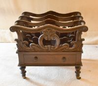 A LATE REGENCY MAHOGANY THREE DIVISION CANTERBURY with single drawer, on turned legs with castors.