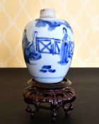 A KANG HSI BLUE AND WHITE VASE painted with figures and fence. 6ins high, on a wooden stand.