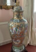 A LARGE CANTON DESIGN PORCELAIN VASE AND COVER, on a wooden stand. 3ft 4ins high.