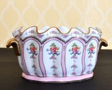 A FRENCH PORCELAIN OVAL SHAPED JARDINIERE painted with panels of flowers, with gilt handles. 11ins