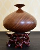 A GOOD HEAVY CARVED WOOD VASE on a stand.