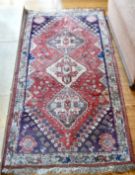 A PERSIAN WOOL RUG with three central medallions. 5ft 6ins x 2ft 9ins.