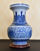 A LARGE CHINESE BLUE AND WHITE VASE with a band of flowers. 14ins high, on a wooden stand.