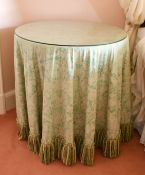 A GLASS TOP CIRCULAR TABLE with fabric cover. 2ft 4ins diameter.