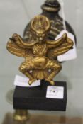 A small Tibetan gilt bronze statue of a mythological beast on stand