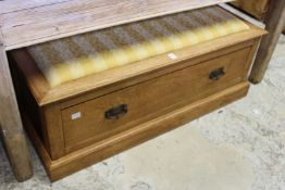 An oak ottoman with a storage drawer