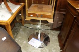 A glass and chrome pedestal table