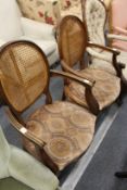 A pair of French style walnut framed open armchairs with canework backs and drop-in seats