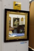 A decorative gilt framed mirror mounted on a velvet back frame