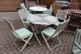 An octagonal shaped folding garden table with four folding chairs with cushions