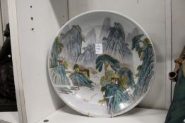 A Chinese famille verte dish painted with a river landscape scene with mountains beyond