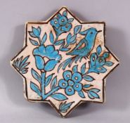 AN IRANIAN TURQUOISE GLAZE STAR FORMED POTTERY TILE, decorated with bird upon branches, 17cm