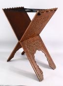 AN ISLAMIC CARVED WOODEN QURAN STAND - carved profusely with scrolling foliate decoration, with