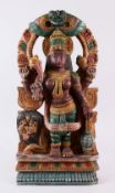 AN INDIAN CARVED WOOD & POLYCHOME FIGURE OF DURGA, depicted with a comical faced lion, four arms