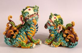 A PAIR OF 20TH CENTURY CHINESE SANCAI POTTERY LION DOGS - the mirrored pair both looking on - one