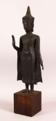 A TIBETAN CAST METAL / BRONZE FIGURE OF BUDDHA - in a stood pose with one hand aloft, mounted to a