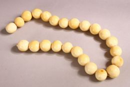 AN IVORY BEAD NECKLACE, comprising 24 spherical beads, largest bead 15mm wide, overall 42cm long.