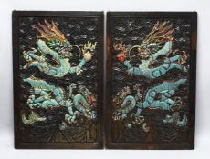 A PAIR OF CHINESE CARVED AND PAINTED HARDWOOD PANELS, depicting dragons each holding the pearl of