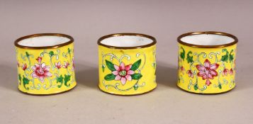 THREE CHINESE YELLOW ENAMEL NAPKIN RING HOLDERS, decorated with formal lotus decoration upon