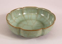 A CHINESE CELEDON SCALLOPED BOWL, the base with calligraphic script, 16cm diameter.