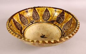 A NISHAPUR YELLOW GLAZED POTTERY BOWL, the centre with a stylised bird, 30cm diameter.