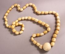 A LONG IVORY BEAD NECKLACE, comprising 62 barrel shaped beads and a large central bead: 25mm wide,