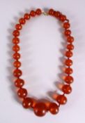 A 19TH CENTURY CHINESE CARVED AMBER BEAD NECKLACE, comprising 29 graduated size carved amber