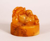 A CHINESE CARVED AMBER COLOUR SOAPSTONE SEAL OF A LION DOG - the dog on its back , the base carved
