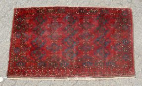 A SMALL PERSIAN BASHIR RUG, red ground with three small rows of four motifs. 5ft x 3ft.
