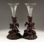 A GOOD PAIR OF BLACK FOREST CARVED WOOD VASE STANDS, one carved as a pair off rabbits, the other a