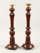A PAIR OF GEORGIAN STYLE MAHOGANY CANDLESTICKS on circular bases. 17ins high