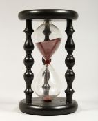 A SAND TIMER IN AN EBONISED STAND 8ins high