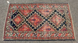 A MID 20TH CENTURY MALAYER RUG, bright red ground with three central lozenges. 6ft 5ins x 3ft