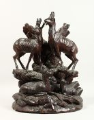 A GOOD 19TH CENTURY BLACK FOREST CARVED GROUP OF THREE DEER on a rocky base. 17ins high
