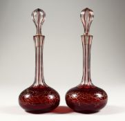A PAIR OF RUBY OVERLAID AND GILT DECORATED CUT GLASS PERFUME BOTTLES 8.5ins high