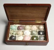 A COLLECTION OF FIFTEEN MINIATURE SPECIMAN STONE EGGS, housed in a mahogany box. Box 6ins long