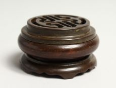 A CARVED CIRCULAR BRONZE PIERCED CENSER on a stand. 2.5ins diameter.