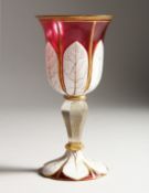 A BOHEMIAN RUBY, WHITE OVERLAY GOBLET with gilt decoration. 7.5ins high