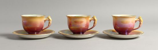 THREE ROYAL WINTON LUSTRE DECORATED PORCELAIN TEA CUPS AND SAUCERS, the handles moulded as birds.