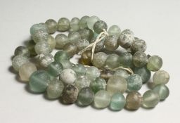 A STRING OF EARLY GREEN GLASS BEADS 40ins long
