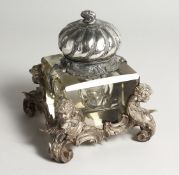 A LARGE CUT GLASS AND PLATED INKWELL IN ROCOCCO STYLE, the corner supports modelled as cherubs 5.