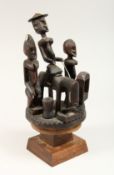 A DOGON TRIBAL CARVED WOOD EQUESTRIAN GROUP, possibly a cover for a box, on a later stand 13ins