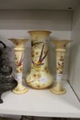 A Crown Ducal blush ivory porcelain three piece vase garniture decorated with exotic birds.