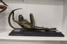 A bronze female reclining nude on a marble plinth base.