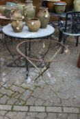 Two wrought iron table bases, one with a circular reconstituted stone top.
