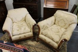 A good pair of upholstered armchairs with carved walnut frames, on claw and ball feet.