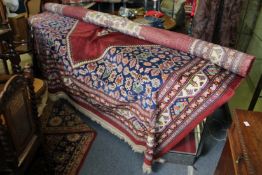 A large Persian style carpet, red ground with geometric decoration.