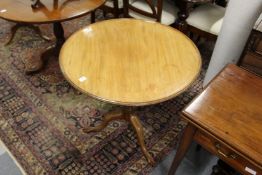 A George III mahogany tilt top tripod table with dished top, turned and carved column supports, on