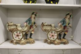 A pair of continental Majolica style dishes modelled as young men pulling a chariot.